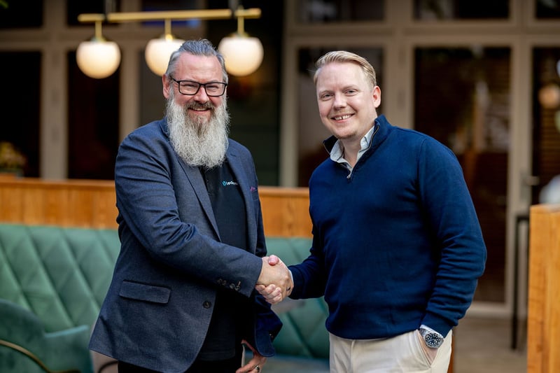 Two men smiling and shaking hands in a lounge